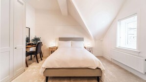 Un dormitorio con cama, mesitas de noche, escritorio y una silla.