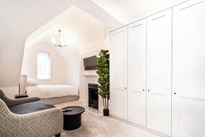 A bedroom with a bed, a chair, a TV, a fireplace, and a wardrobe.
