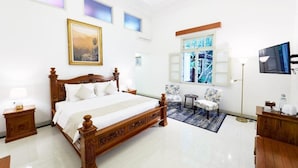 A spacious bedroom with a large bed, a small seating area, and a television. - Tirtodipuran Hotel  (Yogyakarta)