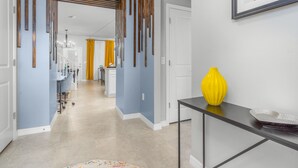 A hallway with a modern design, featuring a yellow vase on a console table and a framed artwork on the wall.