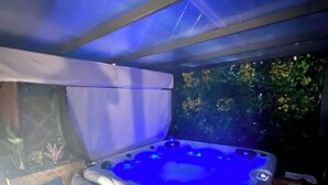 A hot tub with a blue light, a covered seating area, and a view of greenery. - THE CORNER OF THE RIA (Torreira)