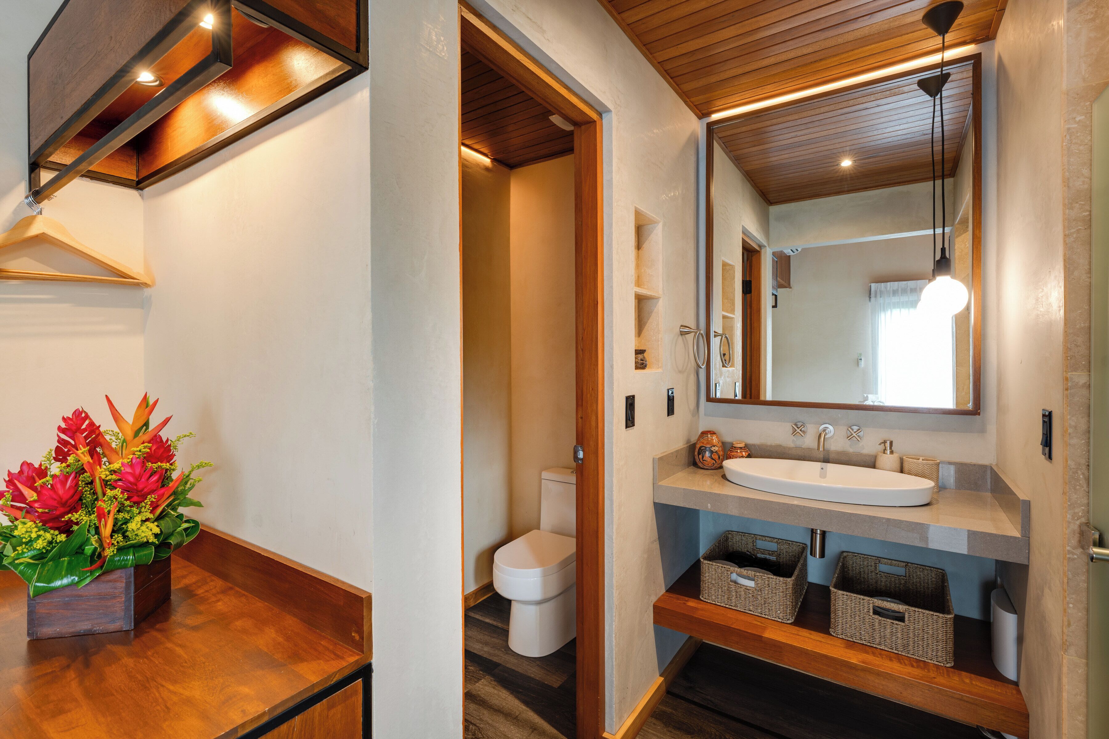 Une salle de bain moderne avec un meuble-lavabo en bois, un grand miroir et un luminaire suspendu.