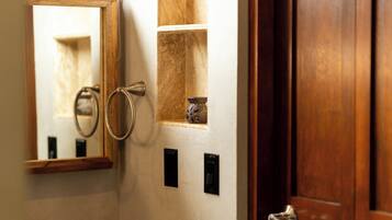 A bathroom with a wooden door, a mirror, a towel ring, and a small shelf with a decorative item.
