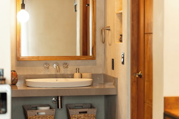 A bathroom with a white sink, a mirror, and two wicker baskets under the sink.