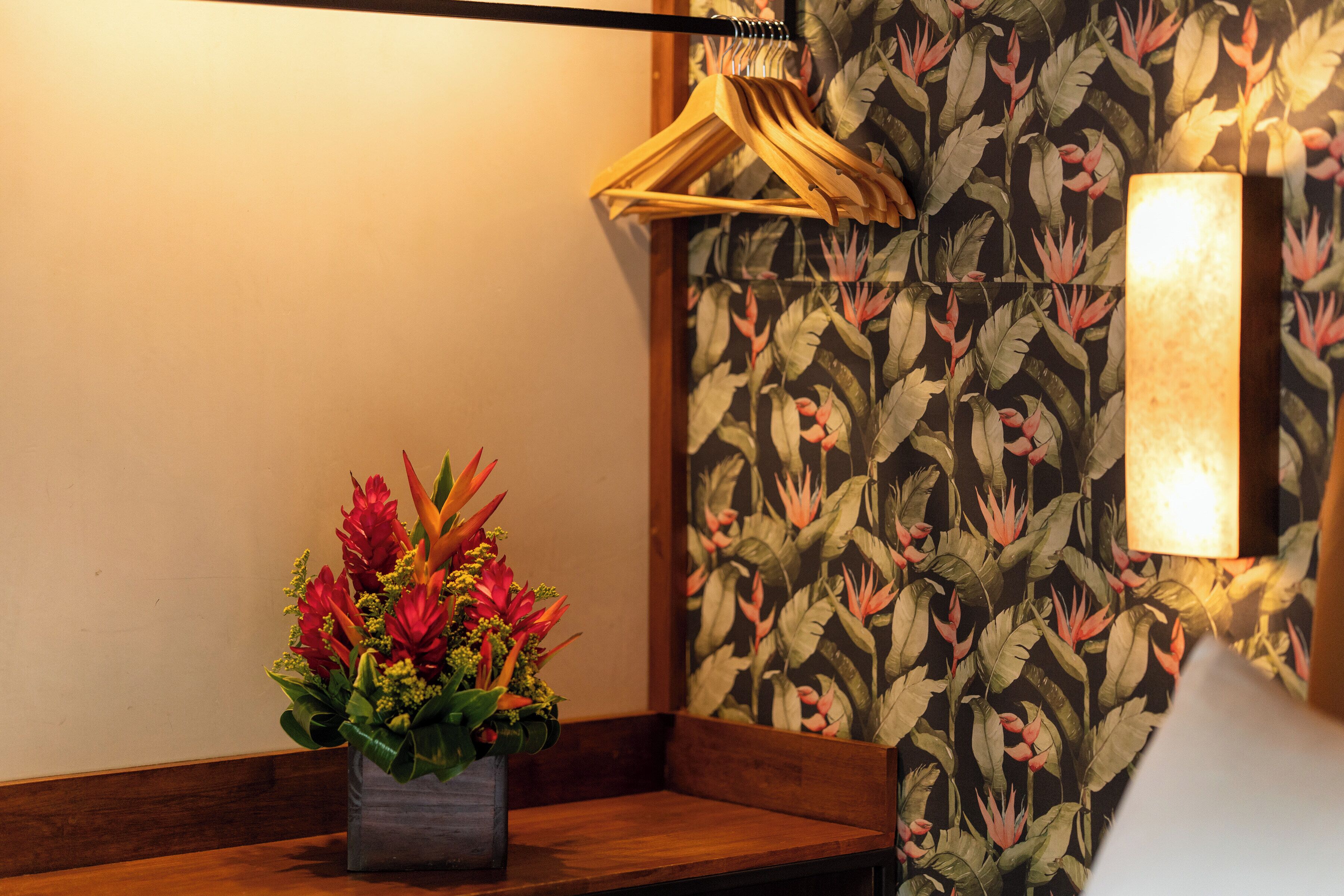 Ein Blick in ein Zimmer mit einer Holzbank, einer Wandleuchte und einem floralen Wandmuster.