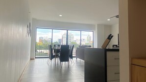Et moderne køkken med et stort vindue, et spiseområde med stole og udsigt til byens skyline.