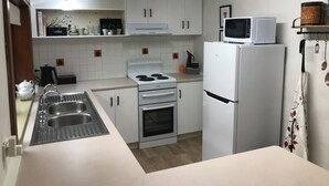 A compact kitchen with white cabinetry, a built-in oven, a microwave, and a sink. - 
Air's Cottage Penola: Colonial stone cottage, WiFi fire AC Spa BBQ dog friendly (Penola)