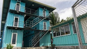 Un edificio de varios pisos con escaleras exteriores, un extintor y un ventanal pequeño.