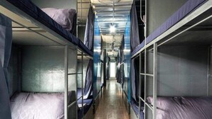 Un vagón de tren con literas metálicas, suelo de madera y un pasillo central.