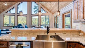 A kitchen with a large island, a sink, and a dining area with a table and chairs. - Pineview Escape - Hot tub, arcade & mountain views (Blue Ridge Mountains)