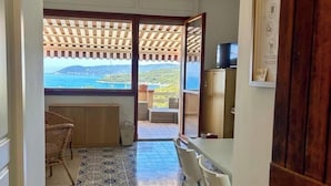 A room with a tiled floor, a ceiling fan, a view through a door to an outdoor area with a pergola, and a dining area with chairs and a table. - Sea view Terrace, Pool, Direct Sea Access in Residence with Tennis (Rosignano Marittimo)