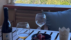 A table with a bottle of wine, two glasses, a bowl of fruit, and a decorative candle holder. - Sea view Terrace, Pool, Direct Sea Access in Residence with Tennis (Rosignano Marittimo)