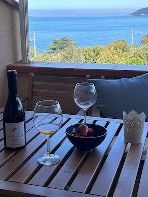 A table with a bottle of wine, two glasses, a bowl of fruit, and a decorative candle holder.