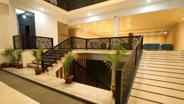 A modern hotel lobby with a staircase, potted plants, and a reception area. - Dolphin club and Resort (Lucknow)