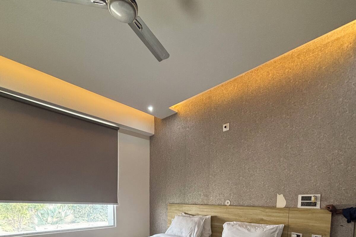 Un dormitorio moderno con una cama de madera, un ventilador de techo, un ventanal con vistas y una mesita de noche con un teléfono.