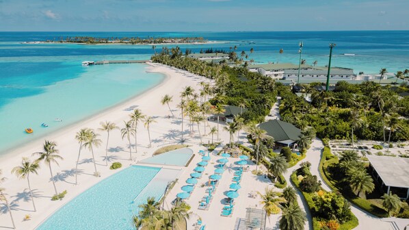 Vista aérea de un resort con una piscina grande, playa y vistas al océano.