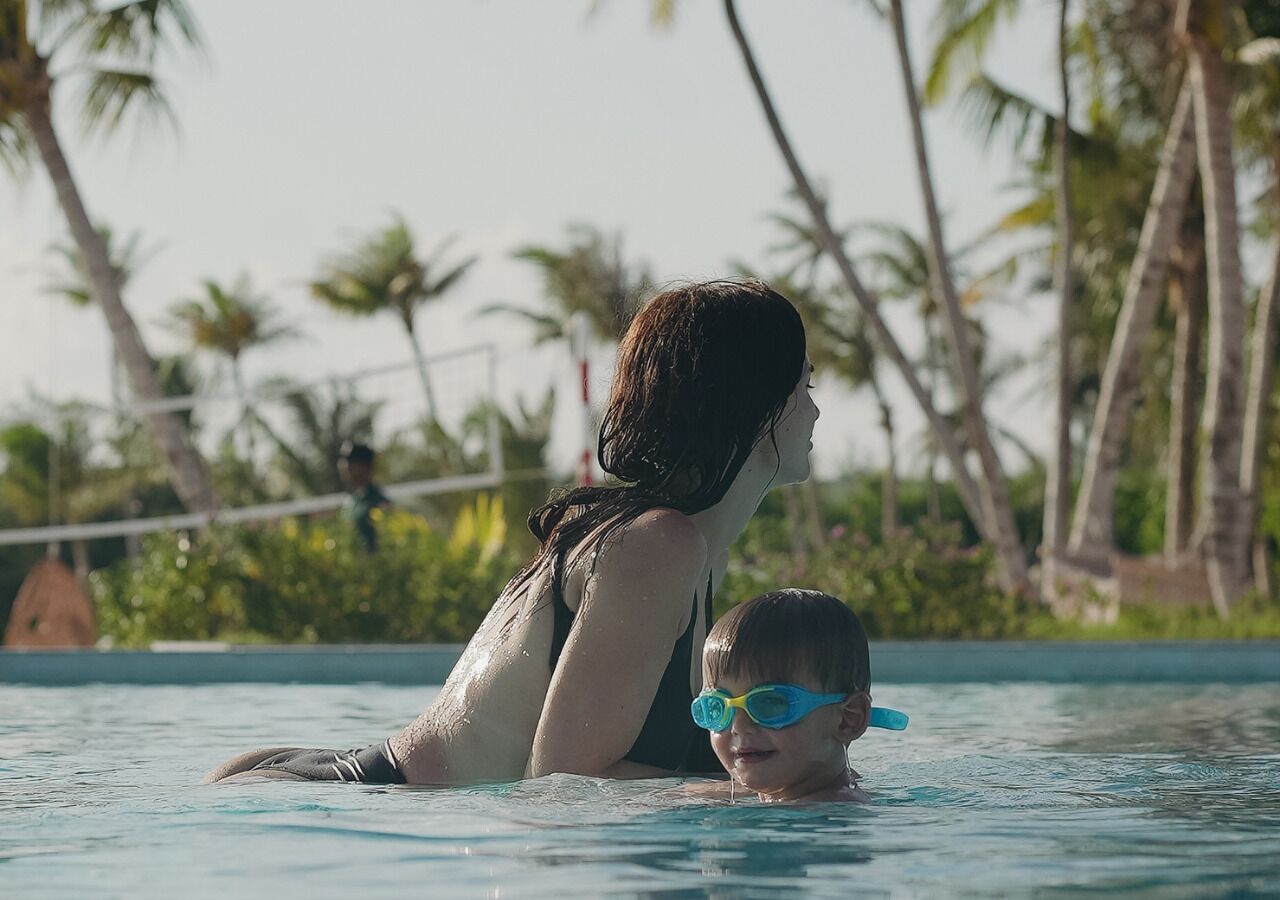 A swimming pool with a person and a child in the water.