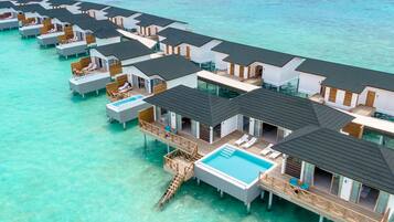 Cabañas sobre el agua con piscinas privadas, conectadas por senderos, ubicadas en aguas turquesas cristalinas.