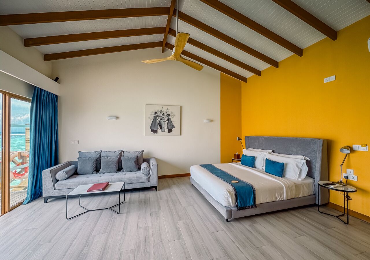 Una habitación de hotel moderna con cama, sofá y mesa de comedor.