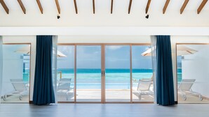 A spacious room with a large sliding glass door leading to a balcony with a view of the ocean. - Joy Island  (Kasanfaru Island)