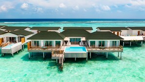 Overwater bungalows with a central pool, connected by walkways, set against a turquoise sea and clear sky. - Joy Island  (Kasanfaru Island)