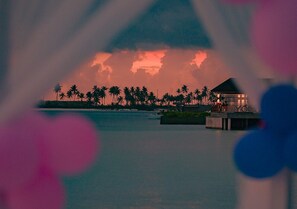 Un resort con un cuerpo de agua, palmeras y un edificio con techo.