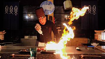 Un chef realiza una flambé con una botella de licor en una cocina.