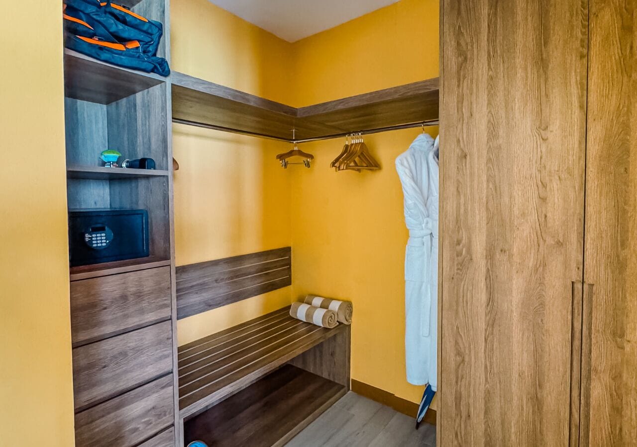 Vestidor con estantes de madera, un banco y perchero.