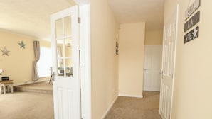 A hallway with beige walls, a white door, and a carpeted floor. There are star decorations on the wall and a sign with words 'SEA LA VIE'. - The Look Out (Norwich)