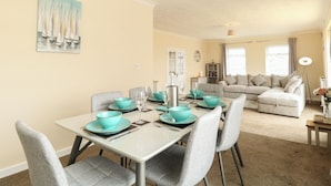 A dining area with a table set for four, grey upholstered chairs, and a teal-colored tablecloth. - The Look Out (Norwich)