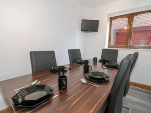 A conference room with a long table, black chairs, and a flat-screen TV mounted on the wall. - Amazing Cottage (Sheerness)