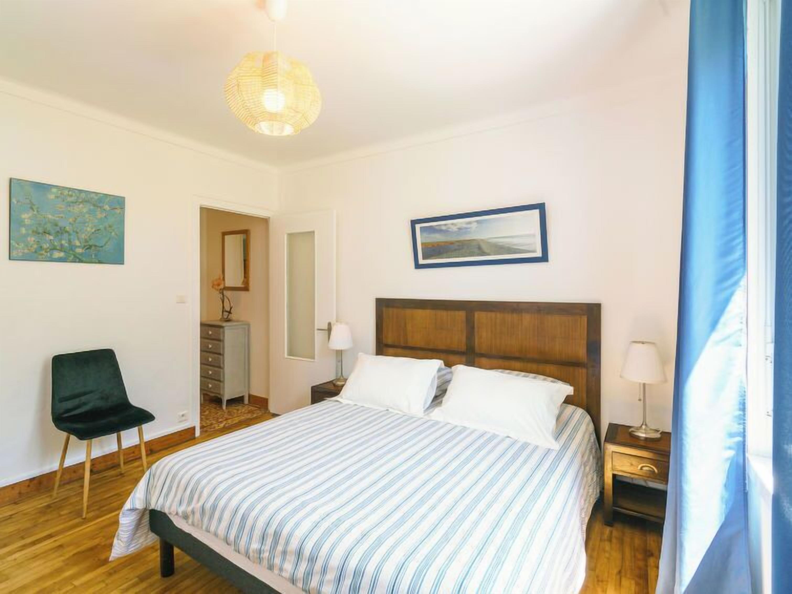 Ein Schlafzimmer mit einem Bett, einem Sessel, einer Kommode und einem Nachttisch.