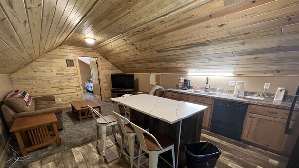 A cozy, rustic cabin with a wooden interior, a dining area with bar stools, a sofa, and a television in the corner. - 20 min to Yellowstone, Loft (Island Park)