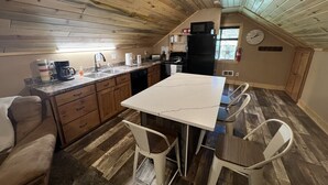 A compact kitchen with wooden ceiling, a white marble countertop, and a dining area with metal chairs. - 20 min to Yellowstone, Loft (Island Park)
