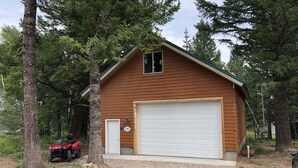 A single-story wooden cabin with a garage, surrounded by trees. - 20 min to Yellowstone, Loft (Island Park)