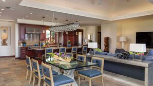 A spacious kitchen with a central island, dining area with chairs, and a living area with a sofa and TV. - Wai'ula'ula Villas 336 Three Bedroom (Kamuela)