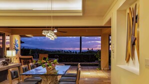 A modern dining area with a glass table, leather chairs, and a chandelier. - Wai'ula'ula Villas 336 Three Bedroom (Kamuela)