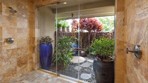 A glass-enclosed shower area with a stone wall, potted plants, and a stone pathway. - Wai'ula'ula Villas 336 Three Bedroom (Kamuela)