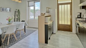 Une cuisine moderne avec un coin repas, comprenant une porte en bois, des placards blancs et un four encastré.