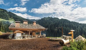 A rustic wooden cabin with a stone roof, surrounded by a forested mountain backdrop. - Buccara Zwischenbachalm  (Westendorf)