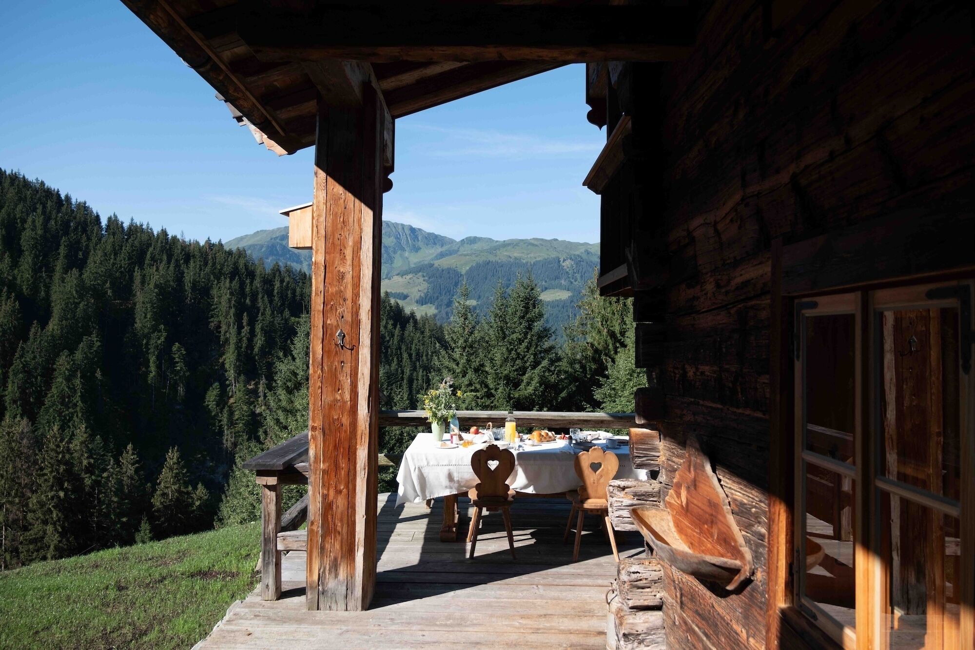 Una cabana de fusta amb zona de menjador que faig a una serralada boscosa.