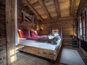A wooden cabin bedroom with a bed, pillows, a statue, and a window.