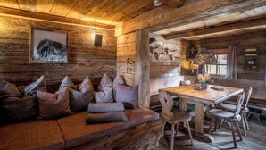 Interior rústico de una cabaña con sofá de madera, una mesa de comedor y una chimenea.