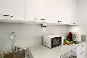 A modern kitchen with a stainless steel sink, a microwave, and a kettle.