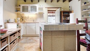 Una cocina con armarios blancos, salpicadero de azulejos y techo de madera.