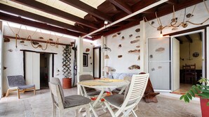 Un área de comedor con una mesa y sillas, una planta en maceta y una pared decorada con piedras.
