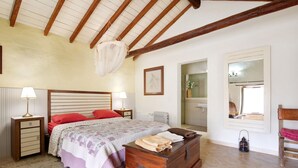 Un dormitorio con cama, lámparas de noche, cómoda, espejo y vista al baño.