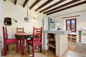 Une cuisine équipée d’une table à manger, de chaises, d’un réfrigérateur et d’une fenêtre.