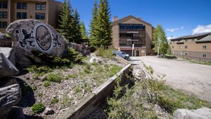 A building with a modern architectural style, a parking area, and a large rock with graffiti. - Designer Ski-In / Ski-Out Condominium At Brian Heads Copper Chase (Brian Head)