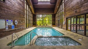 An indoor swimming pool with a hot tub, wooden walls, and large windows. - Designer Ski-In / Ski-Out Condominium at the top of Brian Heads Navajo Lift (Brian Head)